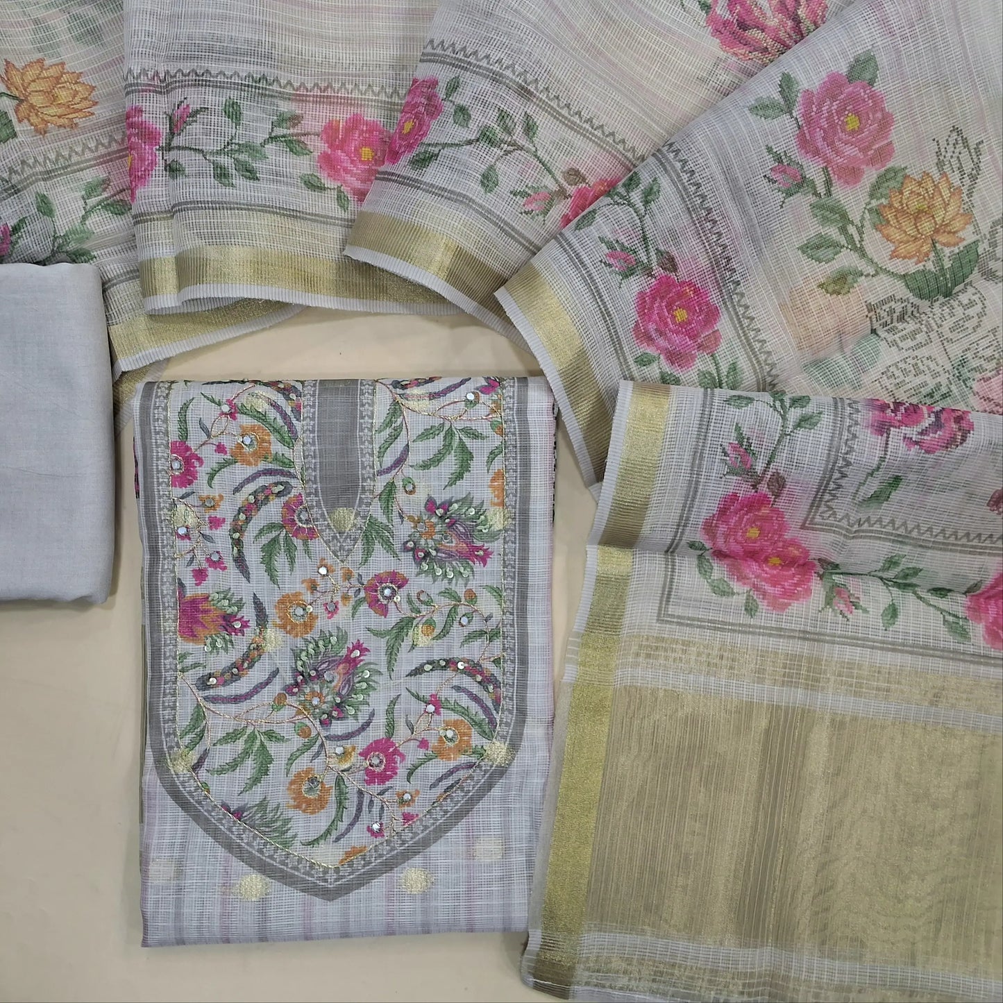 Light grey benarasi chanderi kota unstitched salwar material,digital printed with faux mirror, zardozi work on yoke,zari buttas all over,floral and tissue daman,( lining needed)spun cotton bottom, digital printed kota dupatta with tissue pallu. JL261409