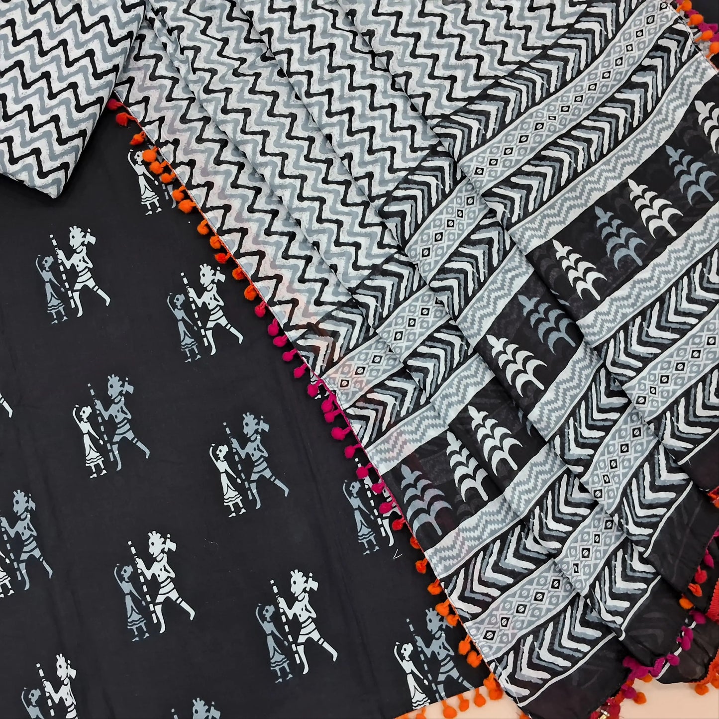 Black pure soft cotton unstitched salwar material, pompom taping on daman,warli printed all over( soft,lining optional)zigzag printed cotton bottom,hand block printed full length mul cotton dupatta with pompom tapping. AP262215