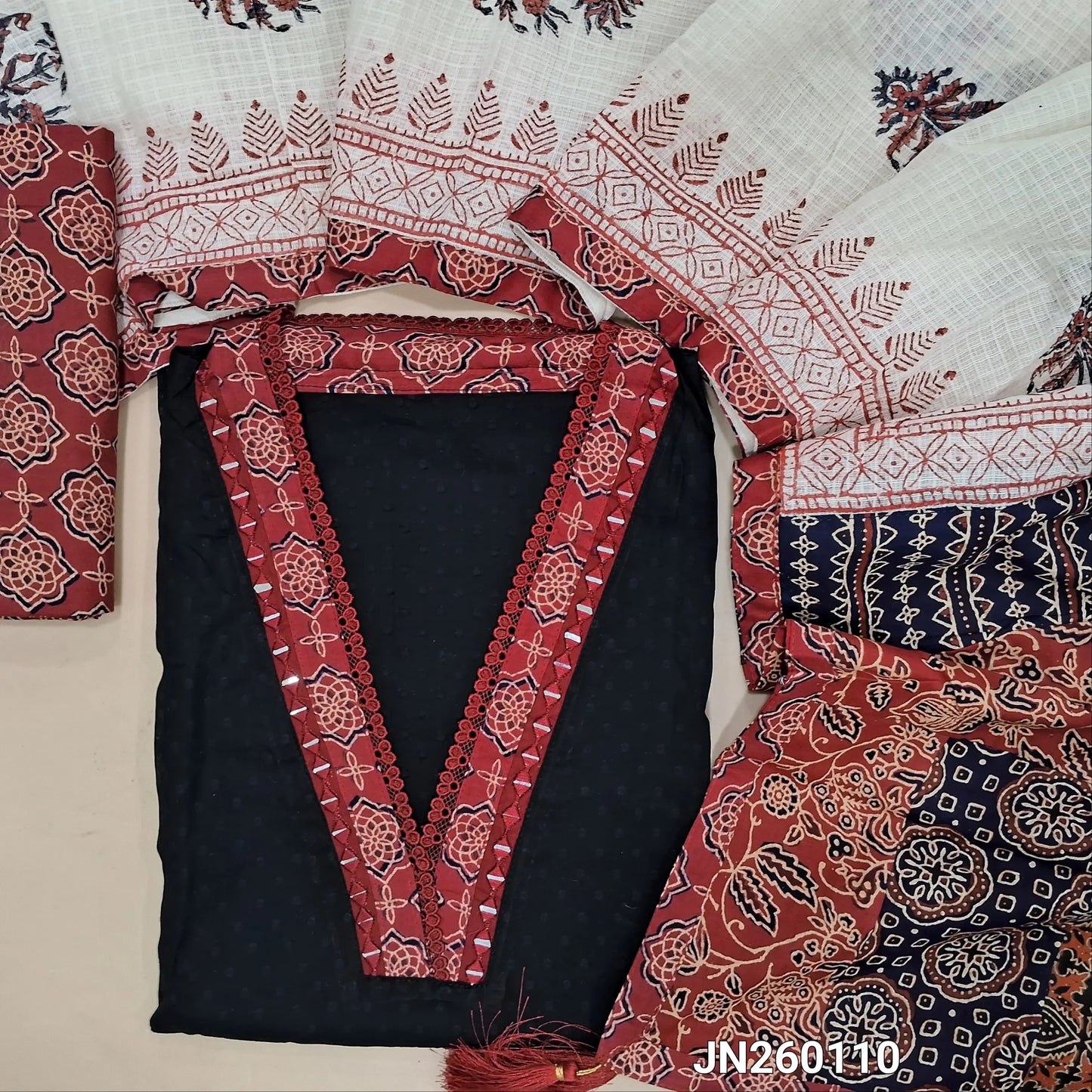 Black premium dobby cotton unstitched salwar material,collar neck with ajrak &real mirror work on yoke, self woven design all over(lining needed) reddish maroon block printed cotton bottom, block printed kota dupatta with applique work on pallu. JN260110