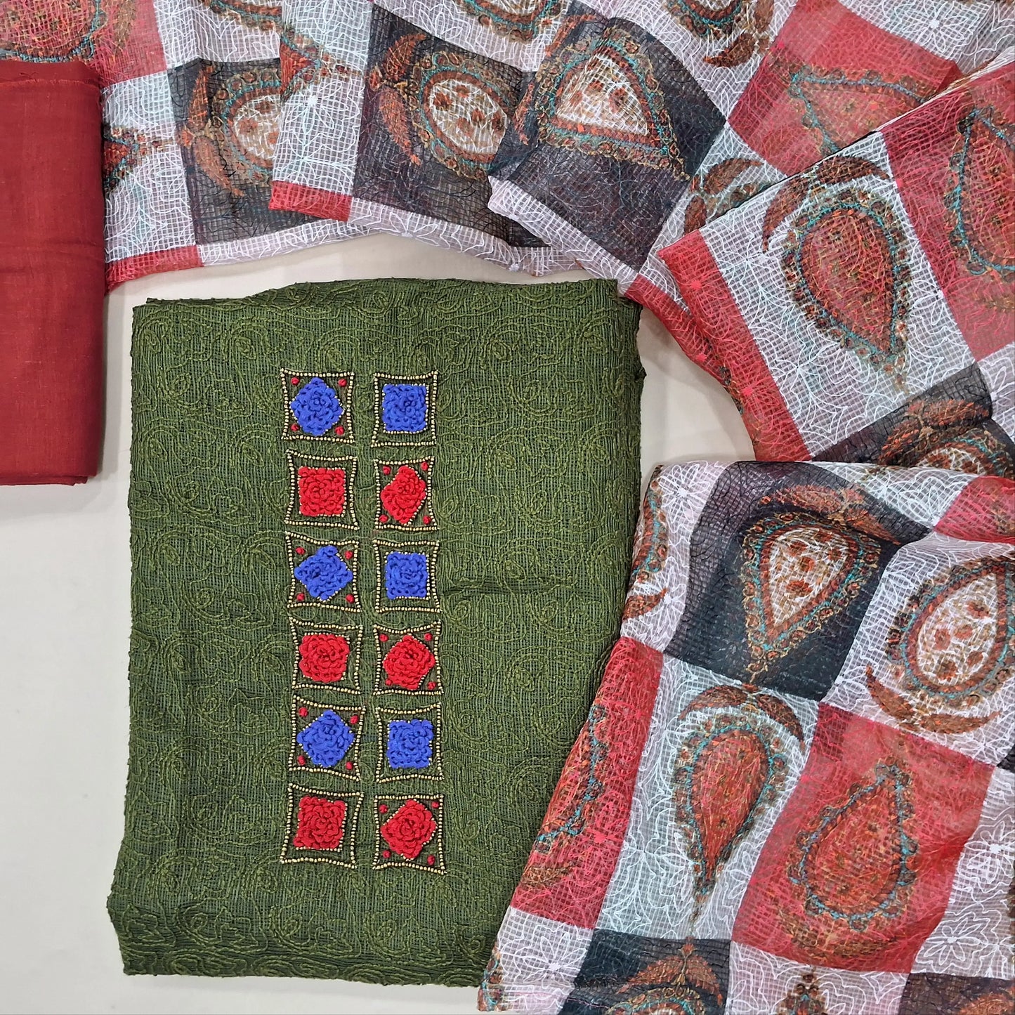 Dark olive green kota unstitched salwar material,french knot work and bead work on yoke,rich embroidery work all over,(Lining Needed)reddish maroon cotton bottom, self embroidery and colourful abstract printed kota dupatta. MY263101