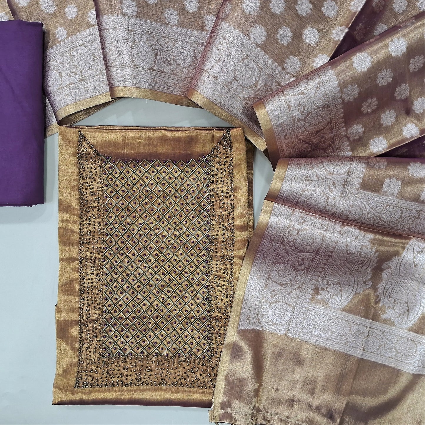 Golden tissue silk with golden tint unstitched salwar material, sugar bead and cut bead work on yoke,(thin, lining needed)purple bottom, benarasi woven tissue silk dupatta with borders and pallu. MY263106