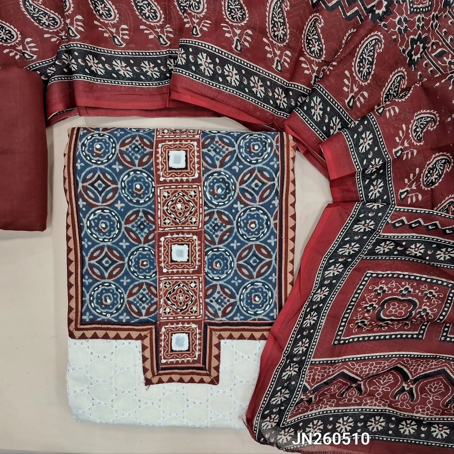Off white base schiffli embroidered pure cotton unstitched salwar material, ajrak yoke patch & hand embroidery with real mirror work on yoke(lining needed) maroon cotton bottom, printed full length pure cotton dupatta. JN260510