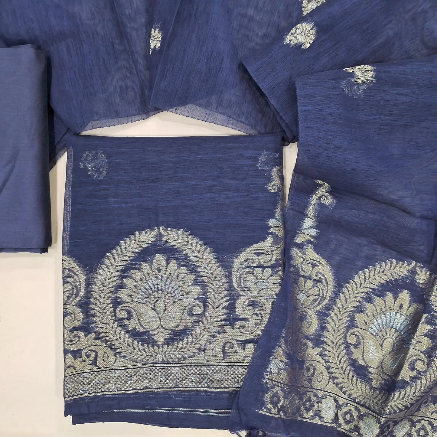 Dark blue tussar unstitched salwar material, zari buttas on front,gold and silver zari weaving on daman,(Lining needed)matching silk cotton bottom,buttas on tussar dupatta with gold and silver zari weaving pallu and tassles. JN261401