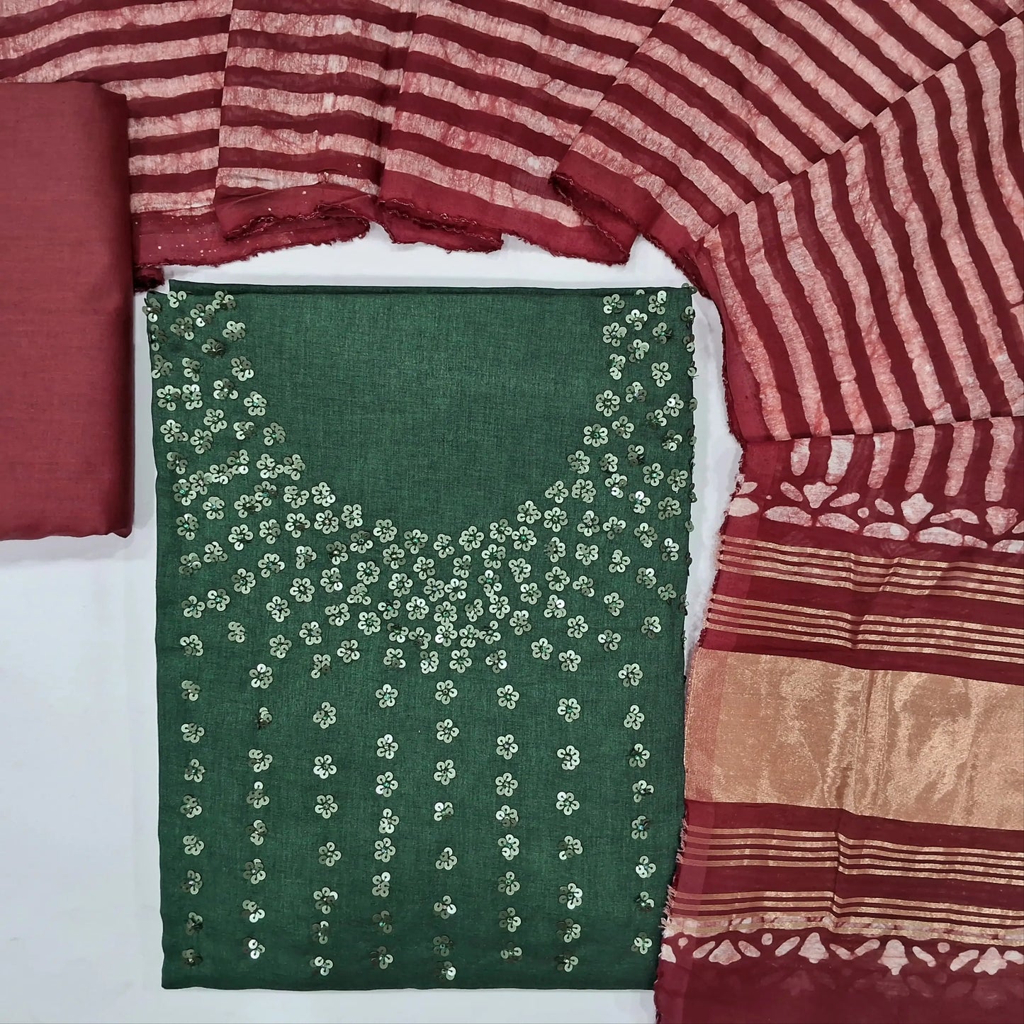 Dark green silk cotton unstitched salwar material (textured, lining needed) floral sequins work on yoke, maroon bottom, batik fancy silk cotton dupatta.(TAPPING NEEDED) JN262104