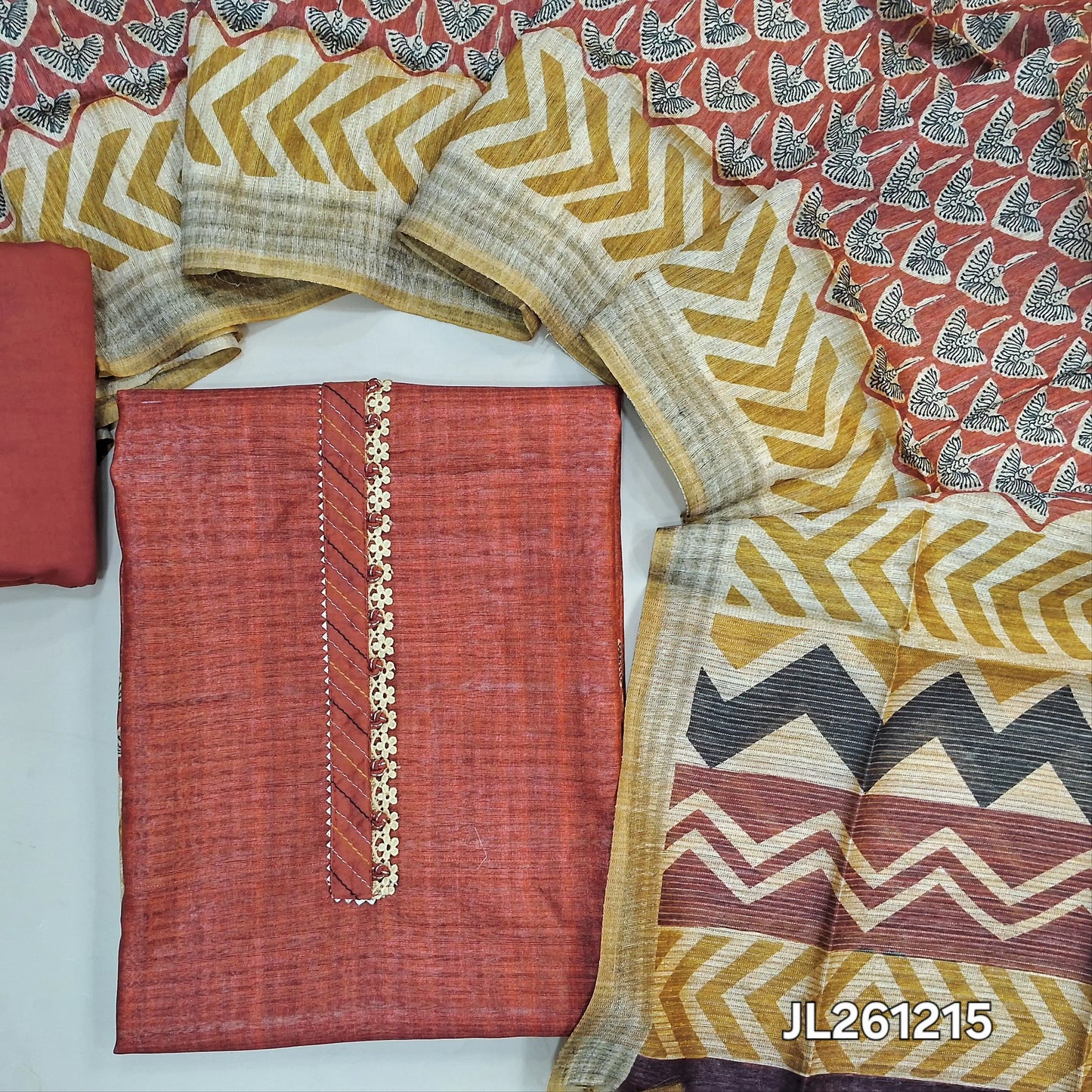 Brick red jute silk unstitched salwar material, potli buttons and lace work on yoke, printed daman,( textured,lining needed)silk cotton bottom,printed jute silk dupatta. JL261215