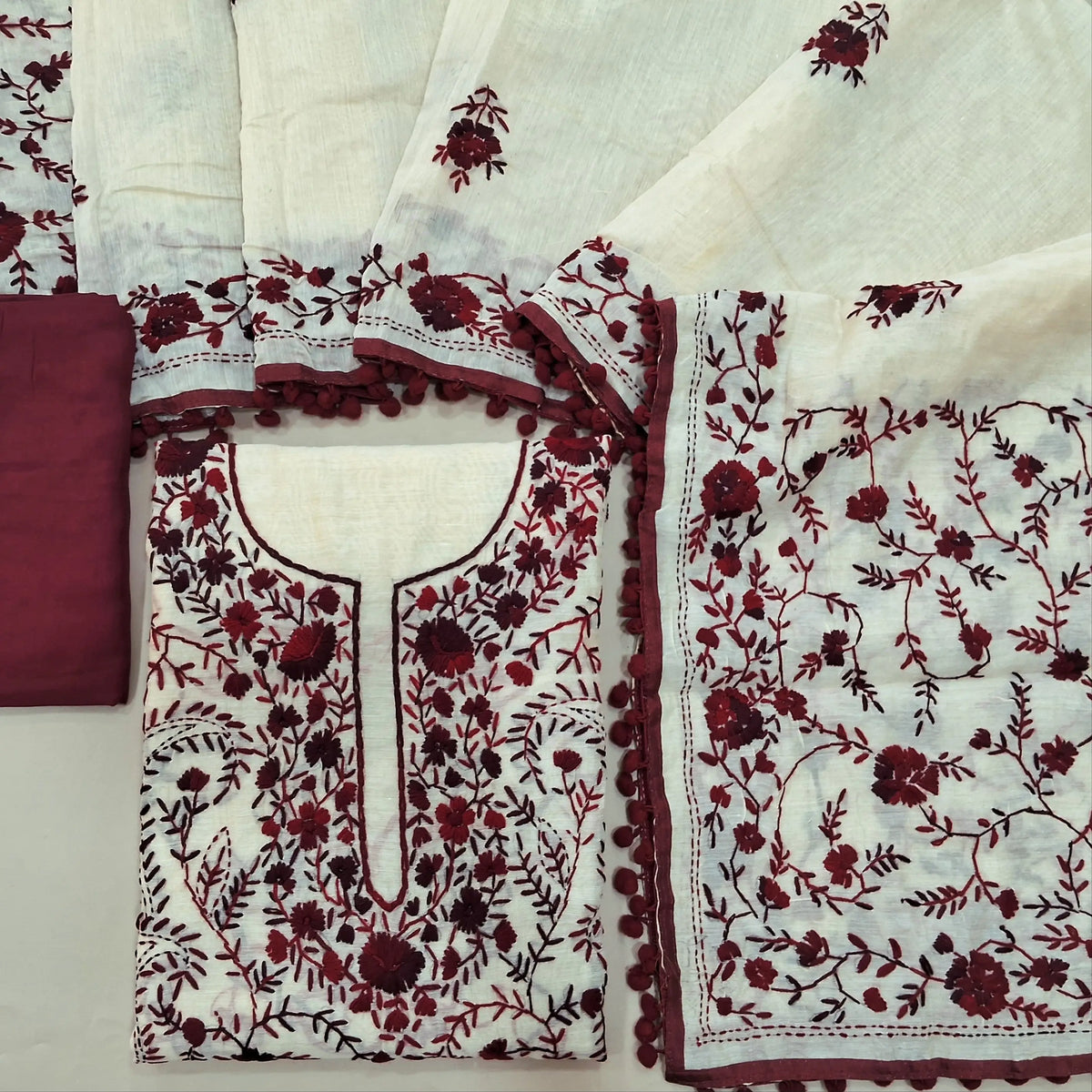 Off white base silk cotton unstitched salwar material,heavy hand embroidery work on front,(EMBROIDERY PATTERN MIGHT VARY)(lining needed) dark maroon spun cotton bottom,silk cotton dupatta with rich pallu and borders with pom pom tapping. SP262118