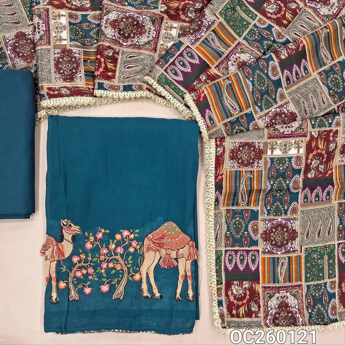 Teal blue mul chanderi unstitched salwar material,printed taping & tassles on yoke,camel design with embroidery on daman,( lining needed)silk cotton bottom, multicoloured digital printed crinkled chinon silk dupatta with lace tapping. OC260121