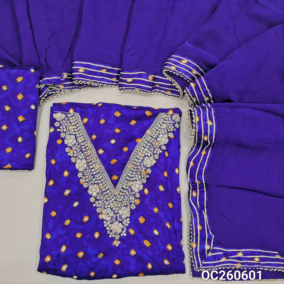 Royal blue pure gaiji silk unstitched salwar material, zarodzi, pearl bead and sequins work on yoke,tie and dye all over,(lining optional)tie and dye gaiji silk bottom, pure organza dupatta with gota and pearl bead tapping and potli bag. OC260601