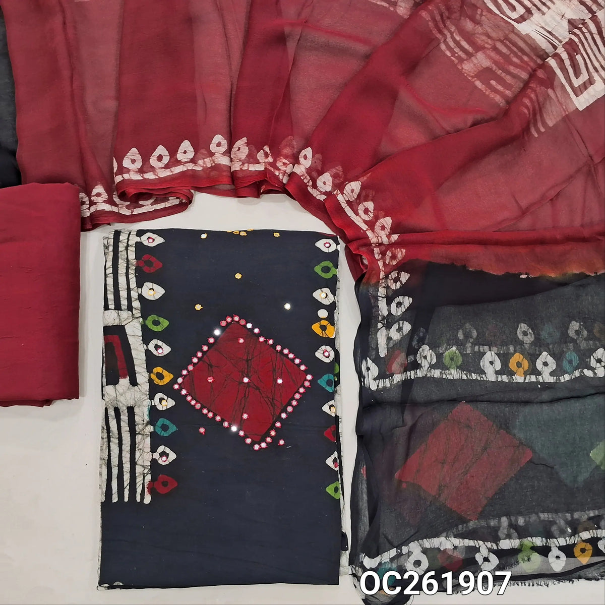 Black base multicoloured wax batik dyed premium satin cotton unstitched salwar material, faux mirror work all over,panel design(lining needed)dark maroon spun cotton bottom, batik design on chiffon dupatta with contrast pallu. OC261907