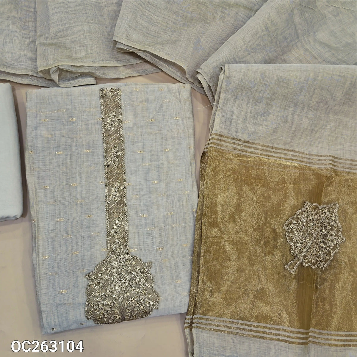 Off white silk cotton unstitched salwar material, zari buttas all over, sequins and tissue aplique work on yoke, gold tissue on daman (Lightweight, Lining Needed) matching spun cotton bottom, silk cotton dupatta with tissue pallu. OC263104