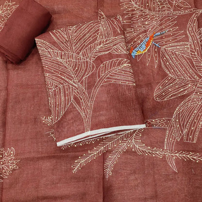 Rust-colored fabric with white embroidered palm leaf patterns and a small blue bird detail