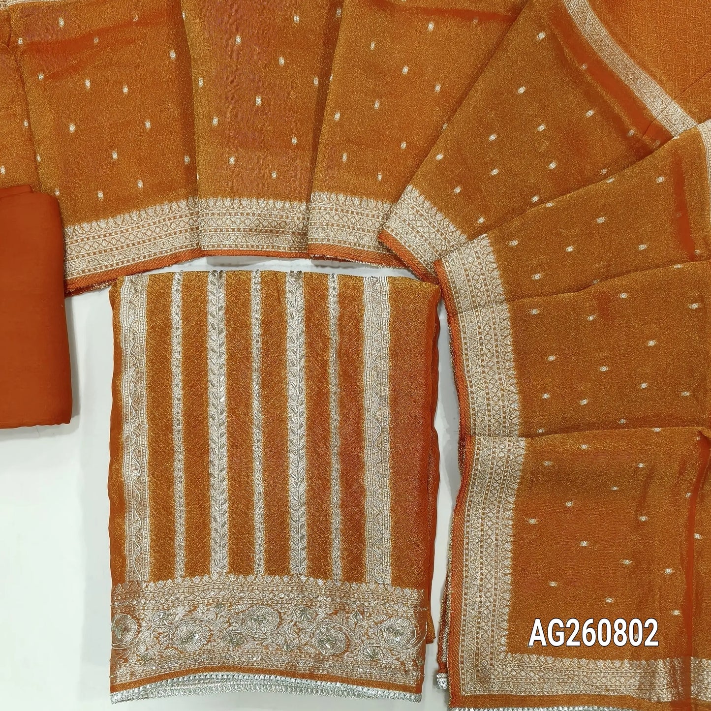 Rust orange with golden tint jakard tissue silk cotton unstitched salwar material,self design all over,cut bead and zardozi work on front, panel design, (Lining Needed)santoon bottom, tissue silk dupatta with zari woven borders. AG260802