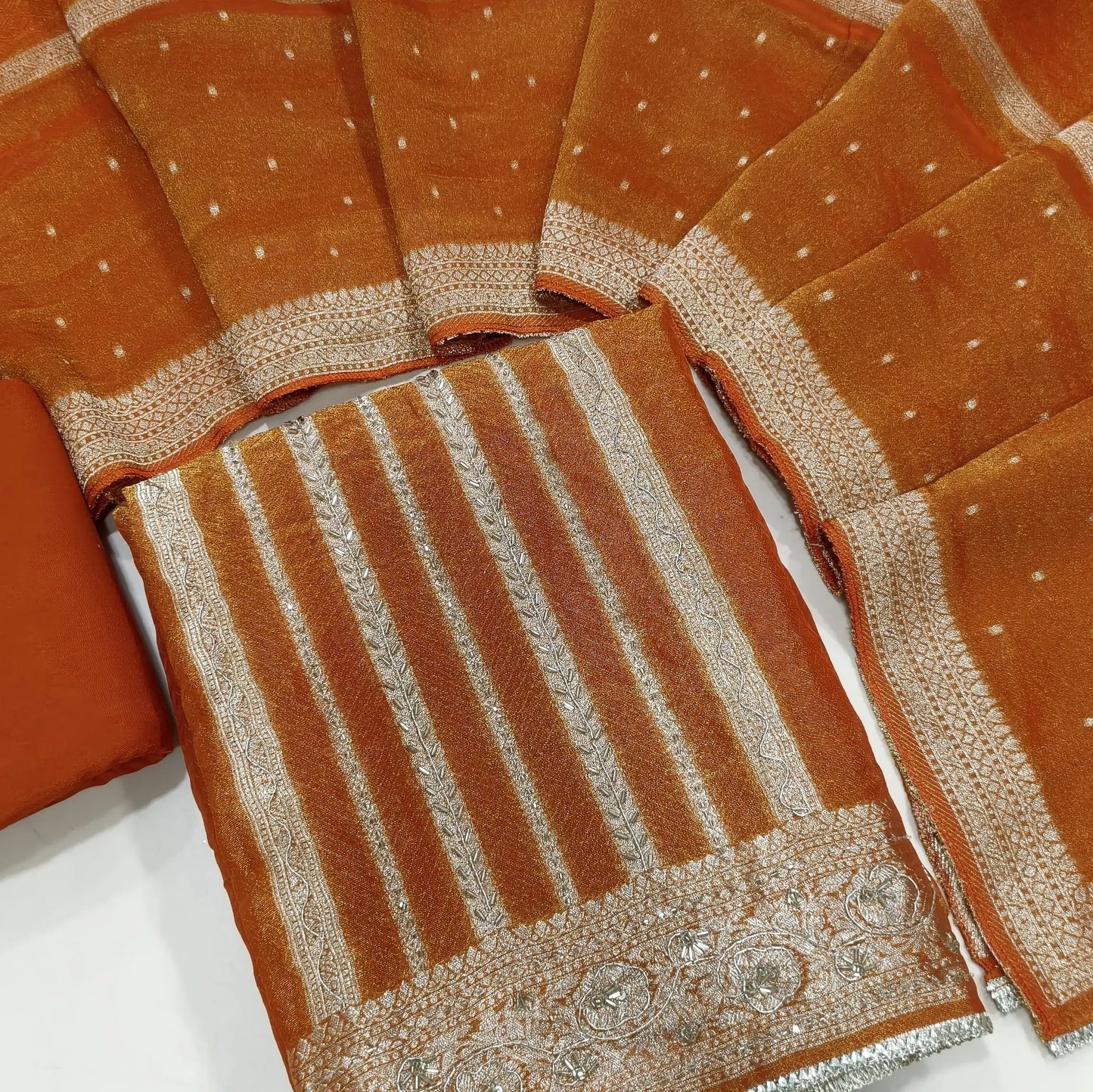 Rust orange with golden tint jakard tissue silk cotton unstitched salwar material,self design all over,cut bead and zardozi work on front, panel design, (Lining Needed)santoon bottom, tissue silk dupatta with zari woven borders. AG260802