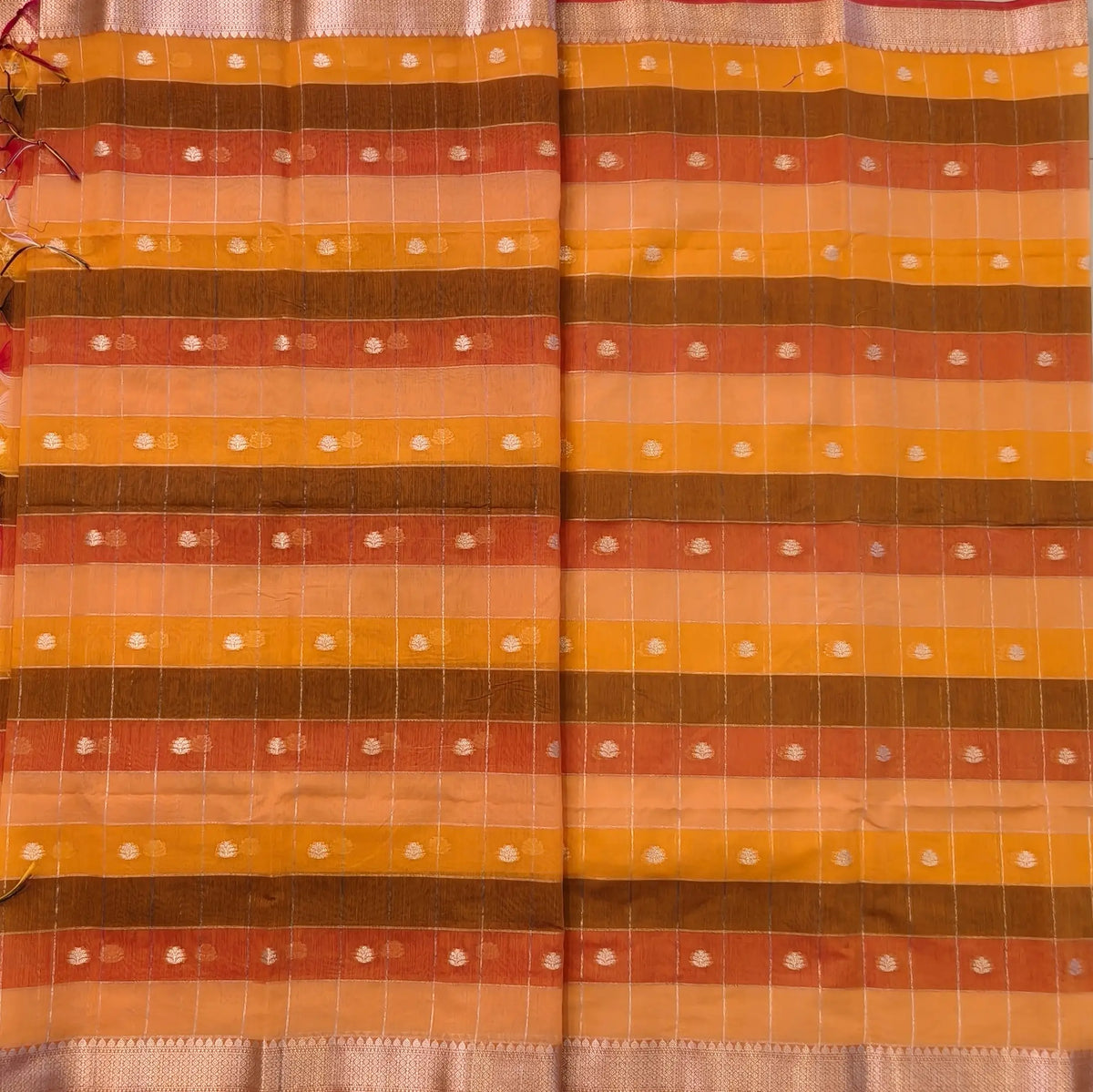 Multicoloured (Orange & yellow)soft silk cotton saree with zari woven checks & buttas all over, zari woven double side borders, tissue pallu,multicoloured running blouse with borders & buttas. NS25