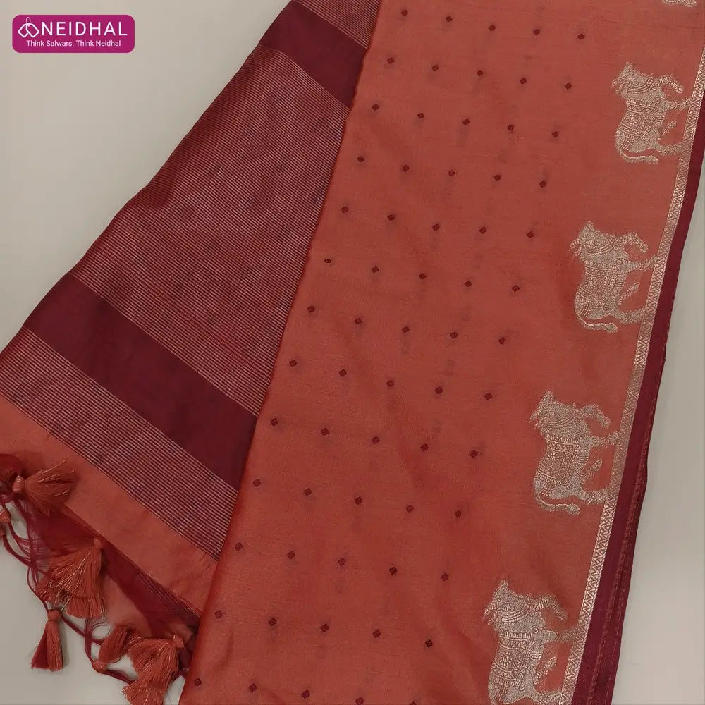 Dark peach with maroon fancy silk cotton saree with thread woven buttas all over the body of the saree, double side borders with pichwai zari short pallu and zari striped blouse with cow motif weaving. CODE NS01