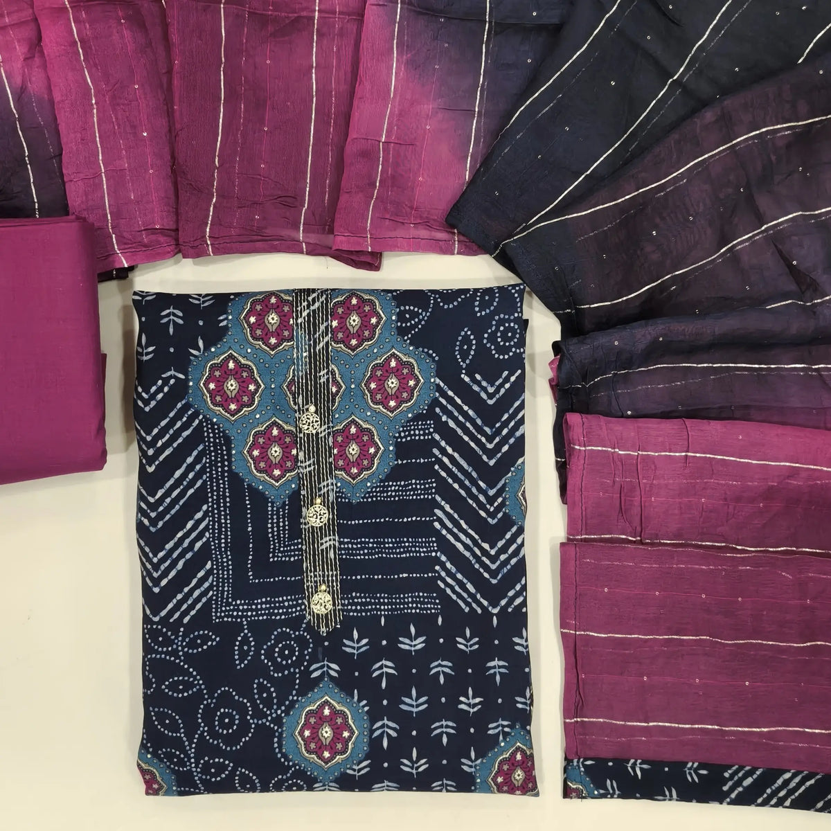 Dark blue printed silk cotton unstitched salwar material, fancy buttons on yoke,(lining needed)beetroot purple cotton bottom,zari lines & sequins on dual shaded fancy silk cotton dupatta. OC261314